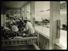 Enfants allités en cure de soleil et d'air pur sur une véranda. Des infirmières prennent soin d'eux.
