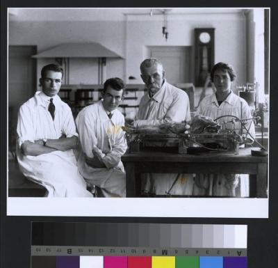 Portrait du Professeur Maurice Arthus (2e depuis la droite) avec ses collaborateurs: à sa droite, son fils André Arthus et le Dr Metkovich, assistant de Belgrade; à sa gauche une femme. Ils sont dans le laboratoire de l'Institut de Physiologie dont le …