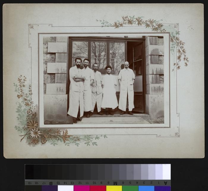 Portrait du docteur Paul Narbel, au centre, fumant un cigarillo avec quatre collègues, dont une femme.