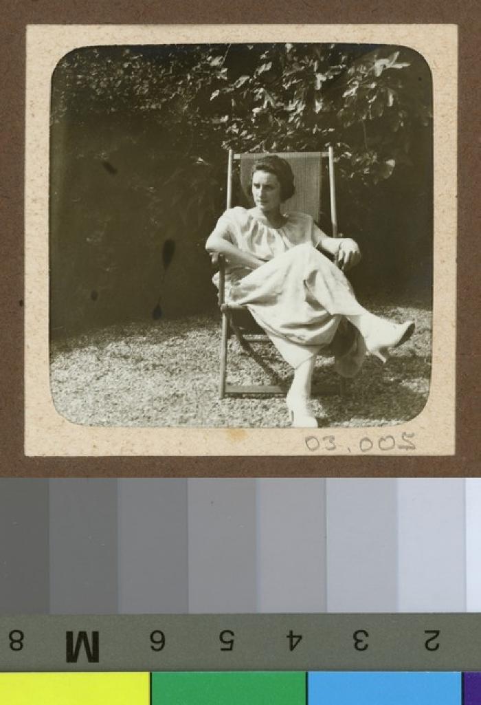 Portrait d'une femme assise sur une chaise dans un jardin.
