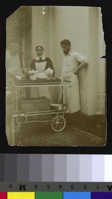 Portrait du Dr Garin accompagné de soeur Stubi et vraisemblablement du Dr Lazare Bégoune, frère d'Anna Bégoune, beau-frère et collaborateur du Dr César Roux, à la salle d'opérations de la clinique du Dr Roux. Devant eux, un chariot avec du matériel pou…