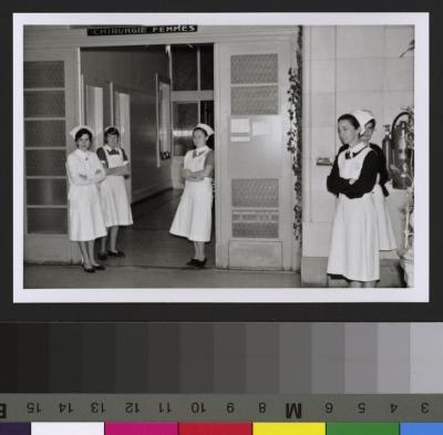 Groupe d'infirmières posant devant la porte d'entrée de la Chirurgie des femmes.