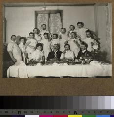 Groupe de médecins attablés dans probablement le réfectoire des médecins de l'Hôpital cantonal, vraisemblablement à l'occasion des fêtes de Noël.