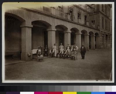 Patients assis dans la cour située au sud de l'Hôpital cantonal (aile est), entourés notamment d'infirmières.