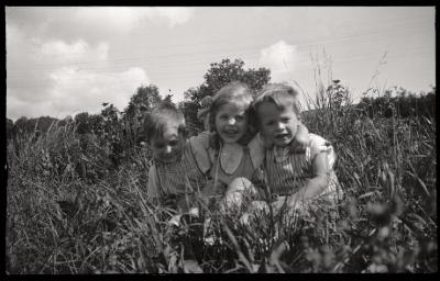 Trois enfants en bonne santé posent au milieu d'une prairie. Ce document était vraisemblablement utilisé pour promouvoir les bienfaits du plein air dans le cadre de la lutte contre la tuberculose.