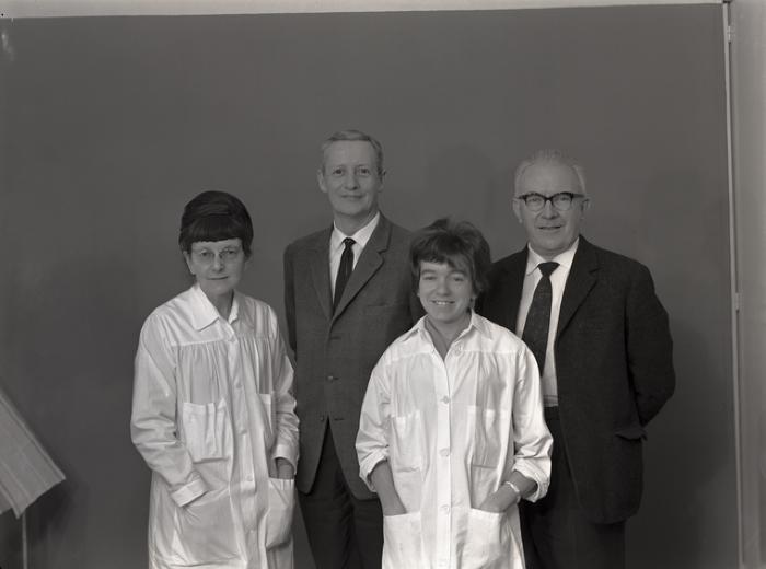 Groupe composé de deux hommes et deux femmes habillées en uniforme de travail.