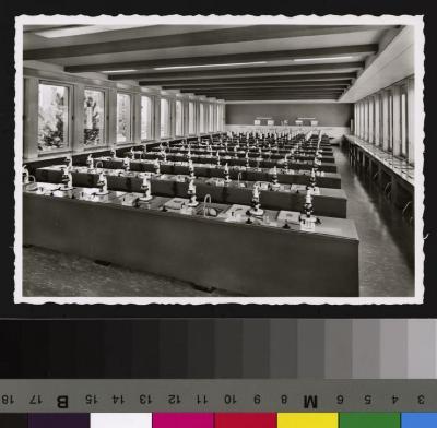Intérieur de la salle de microscopie de la nouvelle Ecole de Médecine. Postes de travail avec microscope, matériel, planches à analyser, robinet et évier, prise électrique.