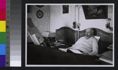 Portrait du Dr. Eugène Olivier (1868-1955) alité, dans sa chambre. Autour de lui des livres, un téléphone. Au mur des prises électriques, une lampe, des tableaux et un miroir. Marié à la doctoresse Charlotte Olivier-Von Mayer, il s'est consacré à la lu…