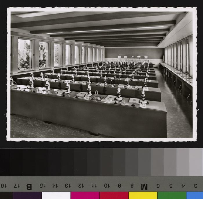 Intérieur de la salle de microscopie de la nouvelle Ecole de Médecine. Postes de travail avec microscope, matériel, planches à analyser, robinet et évier, prise électrique.