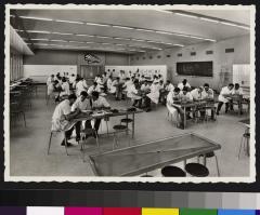 Nouvelle Ecole de médecine (Bugnon), salle de dissection, avec des étudiants travaillant par groupes, assis autour de plusieurs tables.