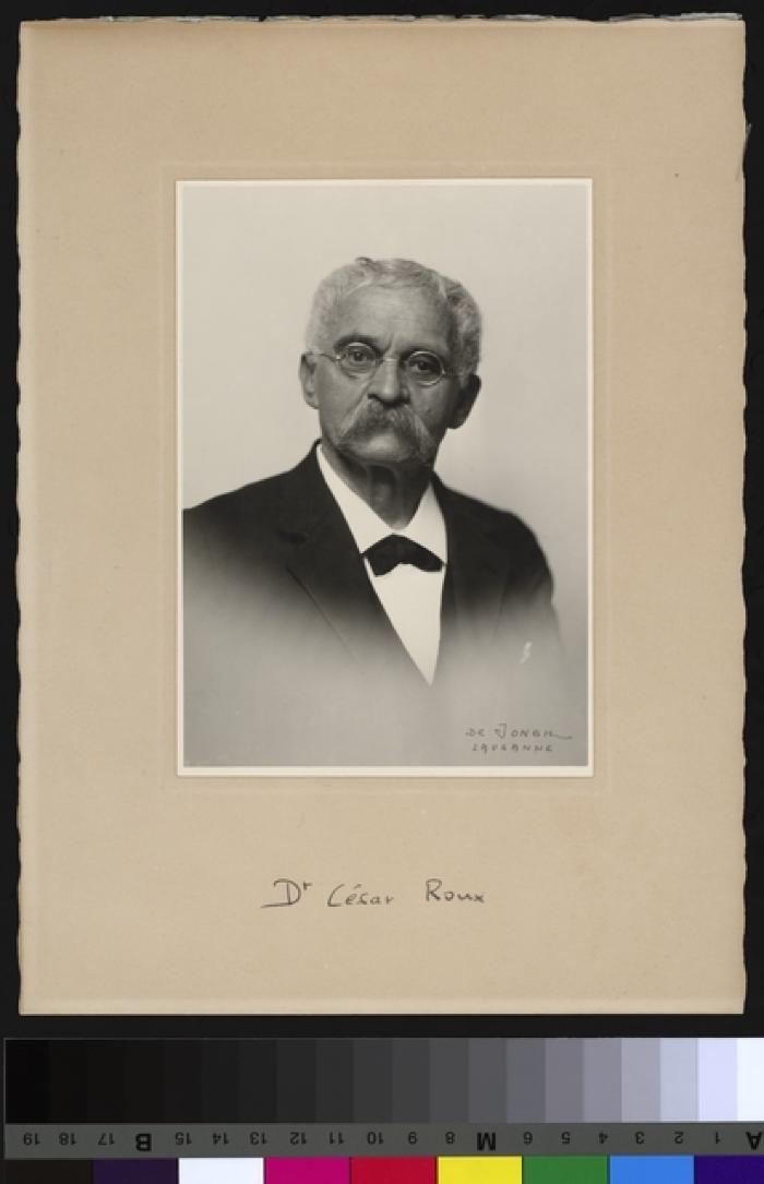 Portrait du Prof. Dr. César Roux, buste, cheveux blancs et moustache grise, de petites lunettes rondes à armatures de fer sur le nez. Il porte un costume trois-pièces.