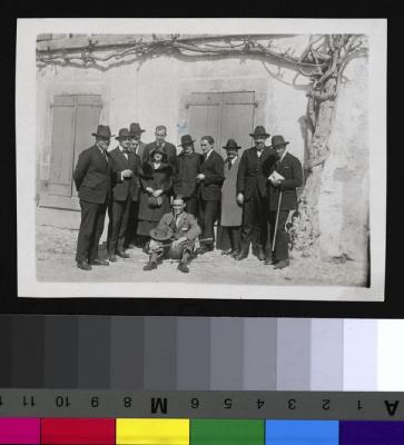 Le Docteur Galli-Valerio, âgé, pose entouré d'un groupe de personnes en habit de ville devant une vieille maison.