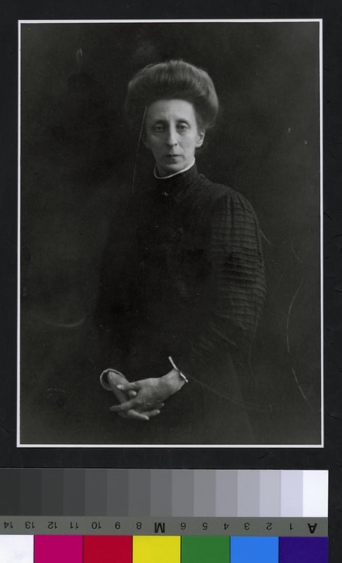 Portrait en pied de la doctoresse Charlotte Olivier-von Mayer (1864-1945). Elle porte une robe noire avec un ourlet blanc au col et aux poignets.