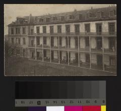 Vue rapprochée de l'aile de l'Hôpital cantonal dévolue aux femmes. Des chaises longues et des bancs ainsi que des femmes sont sur le balcon.