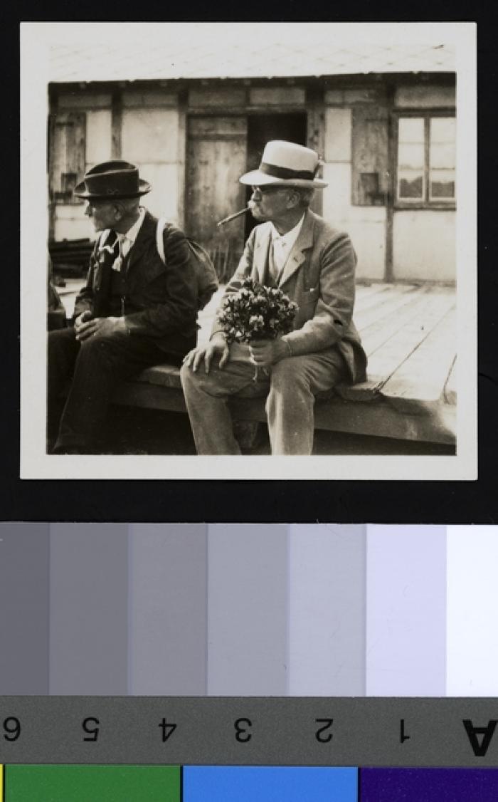 Portrait assis du Prof. Dr. César Roux et du Prof. Paul Demiéville (1855-1947)lors d'une course avec les étudiants de médecine. Le Dr. Roux fume le cigare et tient un bouquet de fleurs dans sa main.