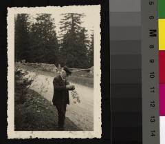 Portrait du Prof. Dr. César Roux âgé, en se promenant. Il est au bord d'un chemin, à la lisière d'une forêt et tient une branche dans sa main.