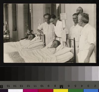 Le Docteur César Roux et vraisemblablement ses assistants rendent visite à deux patientes alitées qui prennent l'air sur un des balcons de l'Hôpital Cantonal.