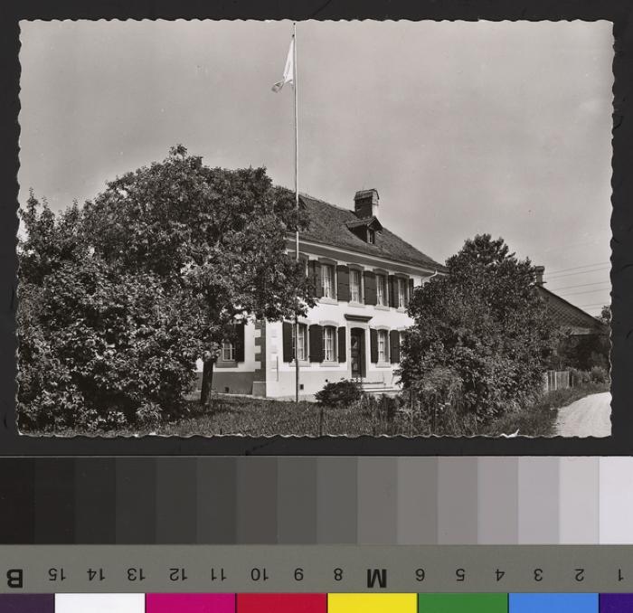 Vue sur la Maison de la Croix Bleue à Servion avec un mât et un drapeau.