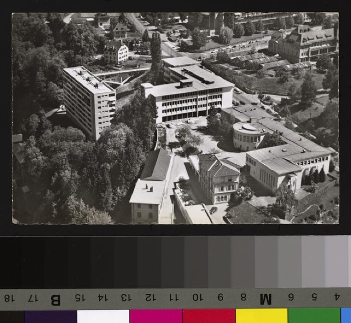 Vue aérienne du quartier des Hôpitaux et de la rue du Bugnon. Au premier plan à droite se trouve l'Institut de Pathologie (1942) avec le grand auditoire et la chapelle ainsi que le Centre anticancéreux romand. Au centre, la construction du Bâtiment des…