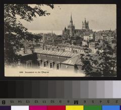Vue sur le quartier de la cité depuis le nord-est. Au premier plan, on aperçoit le toit de l'Hôpital cantonal. A l'arrière plan s'élève la cathédrale avec le lac derrière. A gauche ressort le clocher de Saint-François.