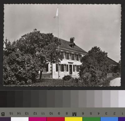 Vue sur la Maison de la Croix Bleue à Servion avec un mât et un drapeau.